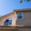 a man standing on the roof while holding a solar panel